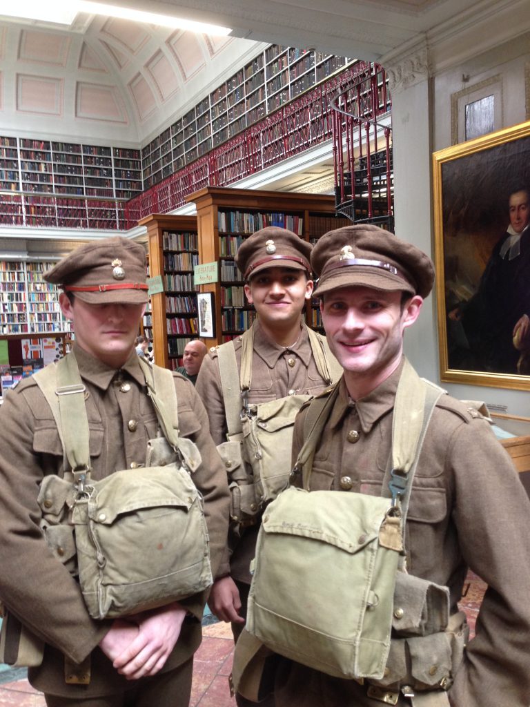 Three young actors dressed up as WW1 soldiers in the Lit & Phil library, Newcastle upon Tyne