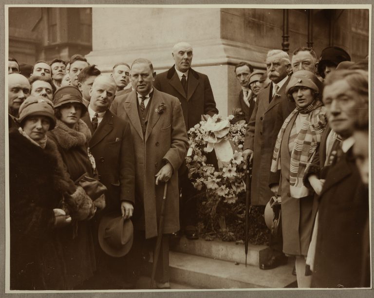 Black and white photo of Blackburn Rovers directors and their families placing a wreath at the Cenotaph in 1928, dressed in smart clothes and grouped round the wreath, looking solemnly at the camera.