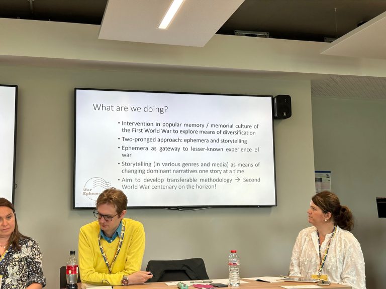 Three project team members sitting in front of a projected slide listing project goals